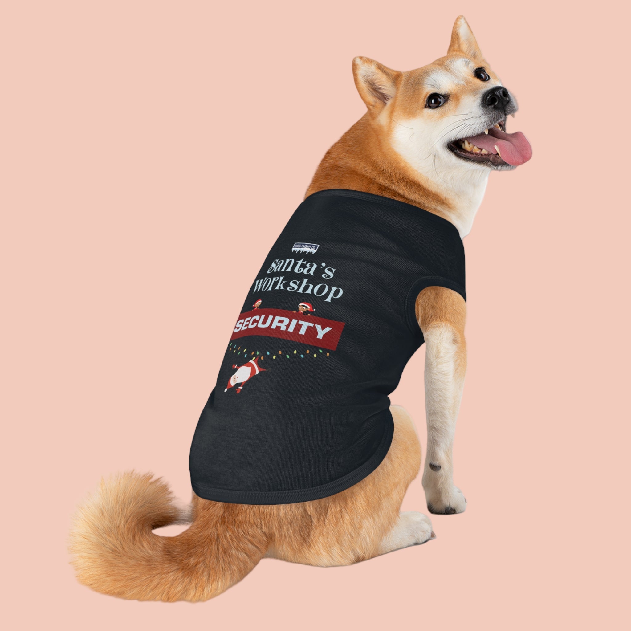 Dog wearing a black t-shirt with 'Santa's Workshop Security' text and graphics on a white background