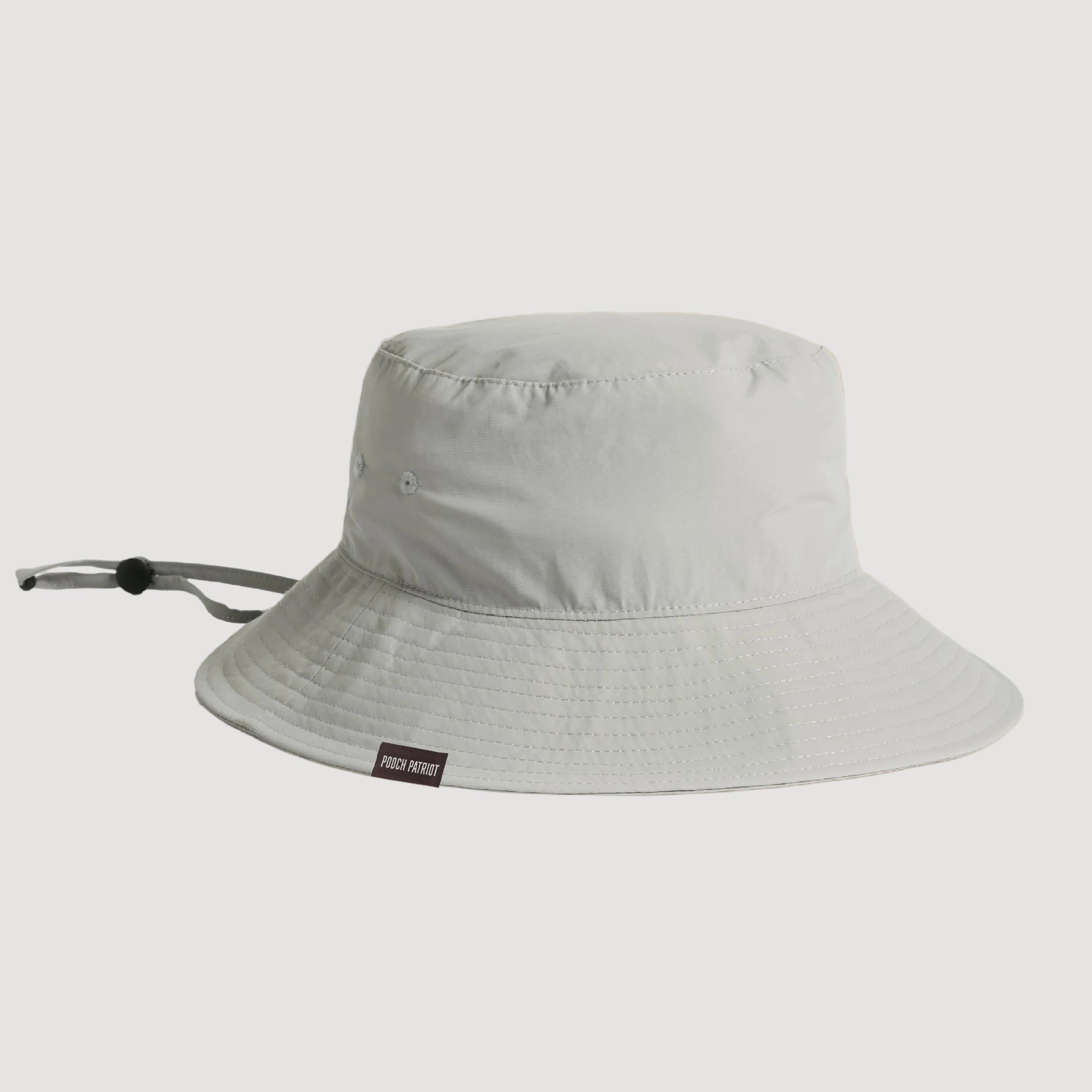 Light gray bucket hat with a brand label on a beige background