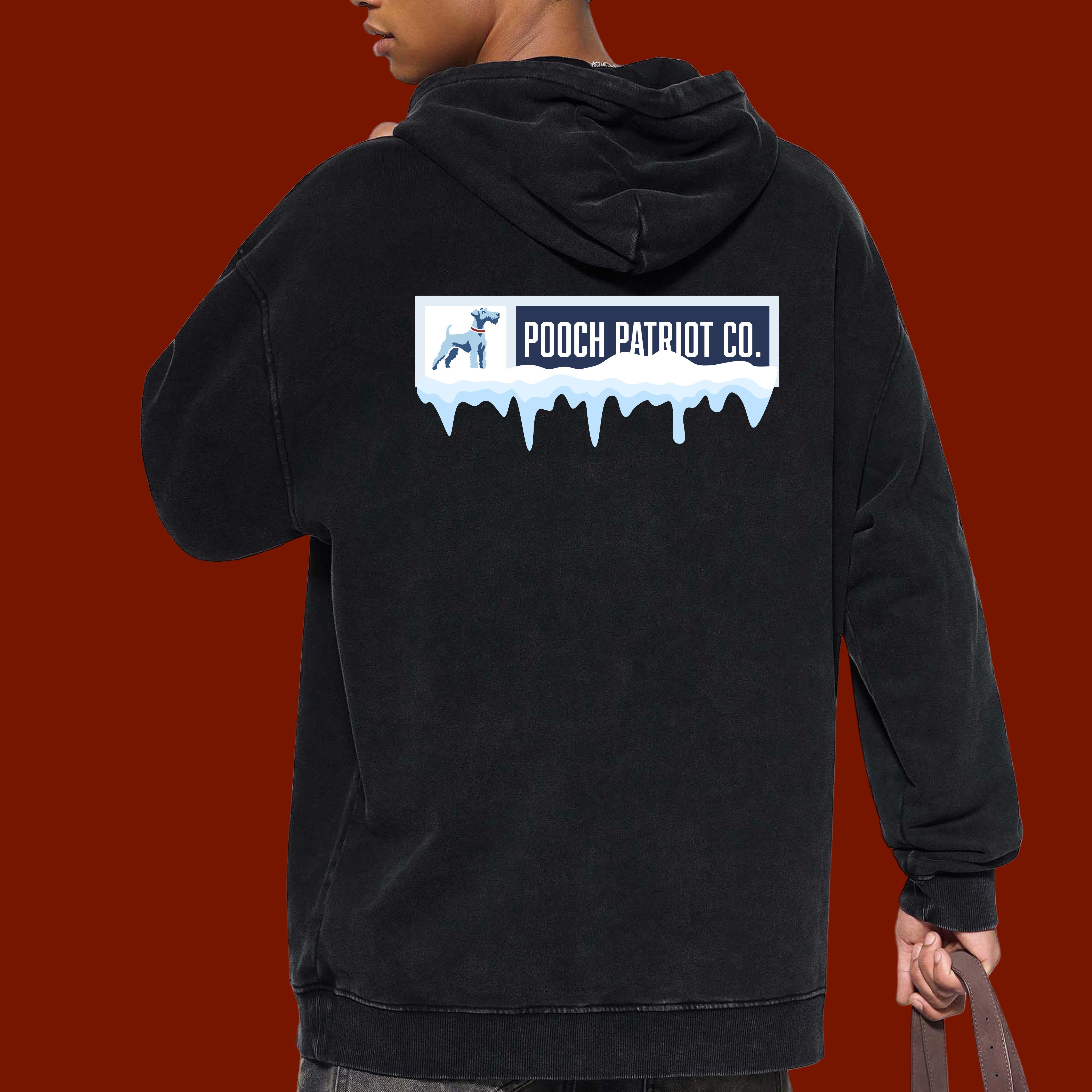 Person wearing a black hoodie with 'Pooch Patriot Co.' logo on the back, holding a brown bag.