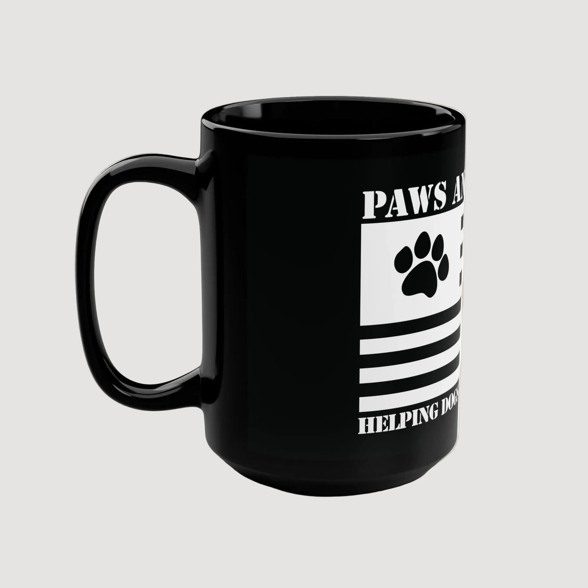 Black mug with paw print design and text on a beige background