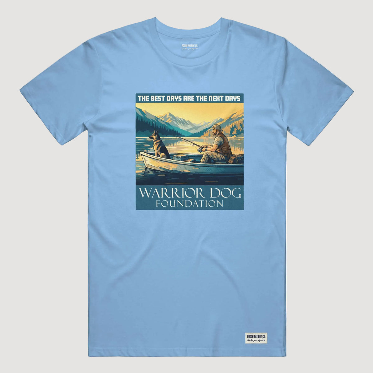 Light blue t-shirt with a graphic of two people in a boat and mountains, featuring 'Warrior Dog Foundation' text.