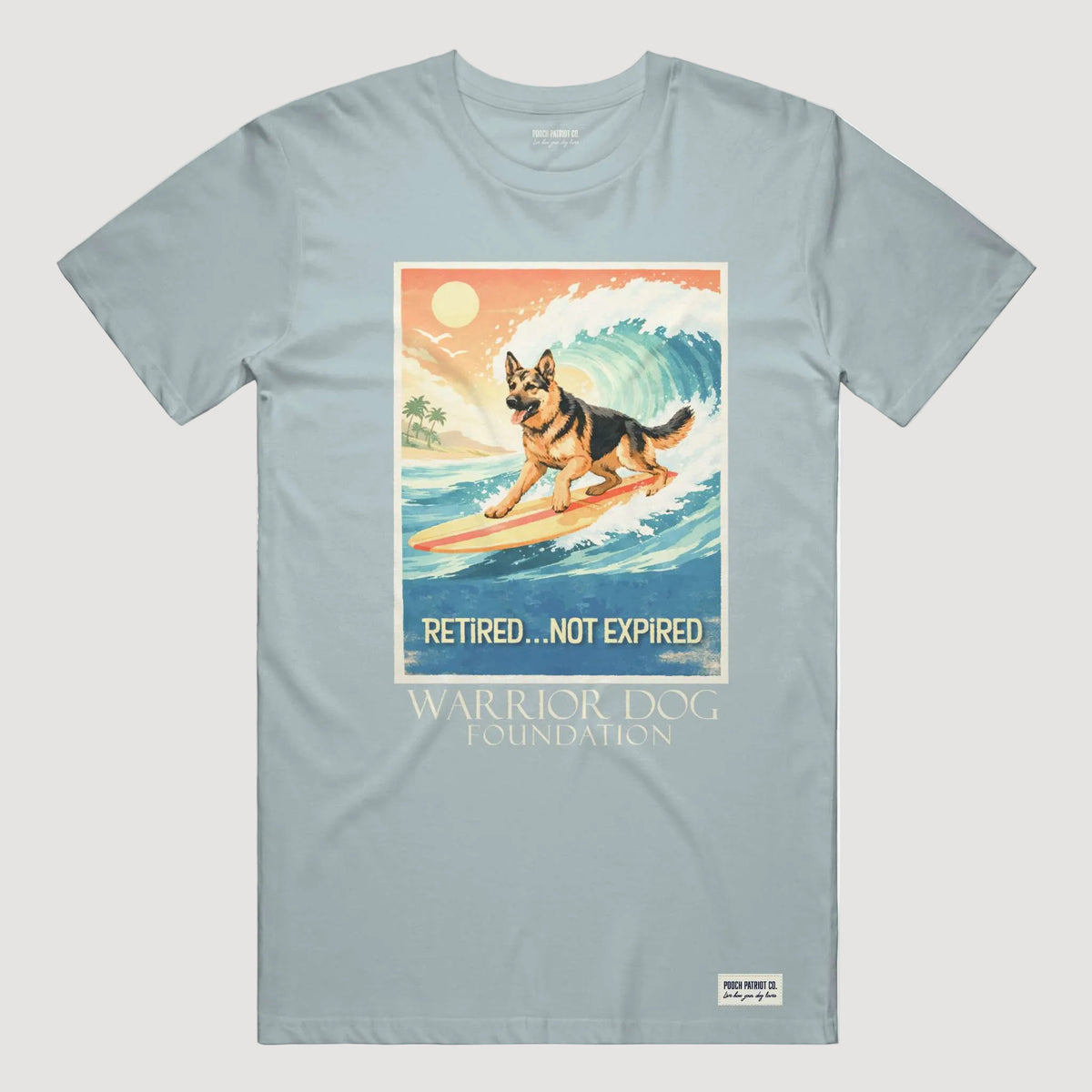 Light blue t-shirt with a graphic of a dog on a surfboard and text 'Retired... Not Expired' by the Warrior Dog Foundation.