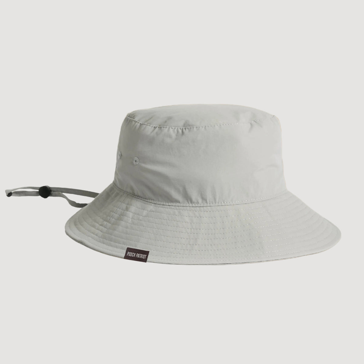 Light gray bucket hat with a brand label on a beige background
