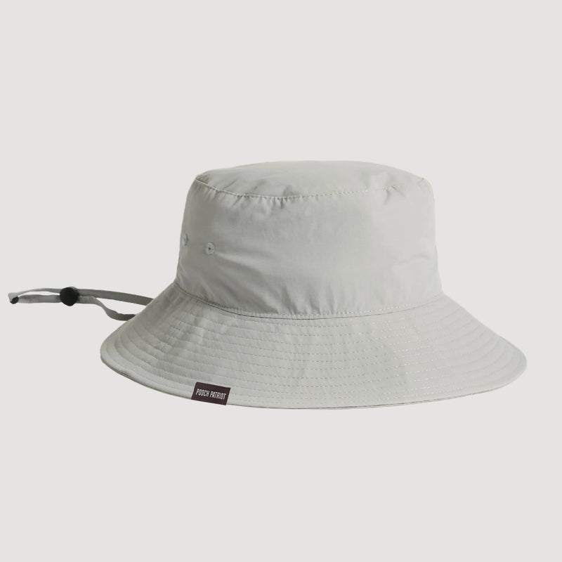 Light gray bucket hat with a brand label on a beige background