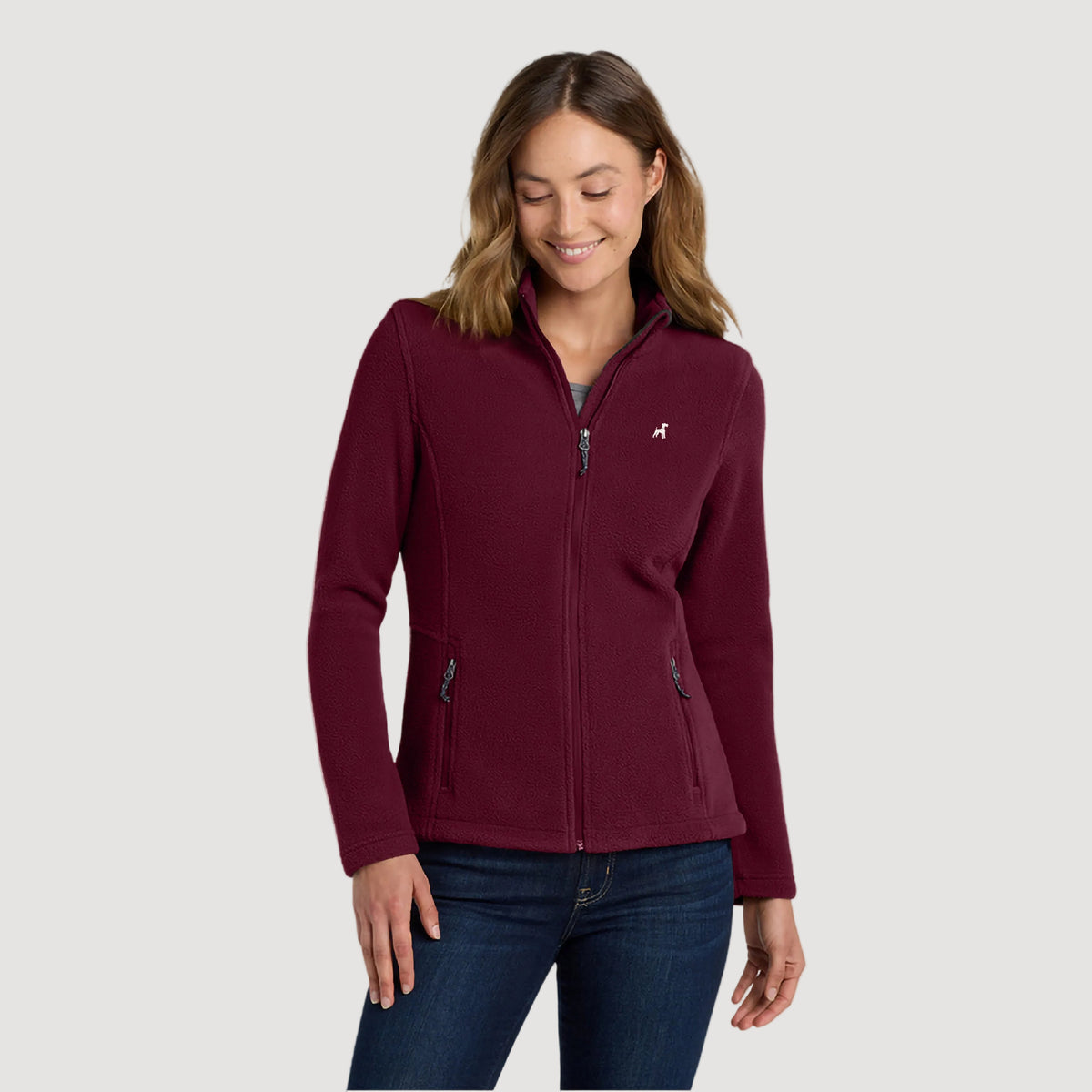 Woman wearing a maroon fleece jacket on a beige background