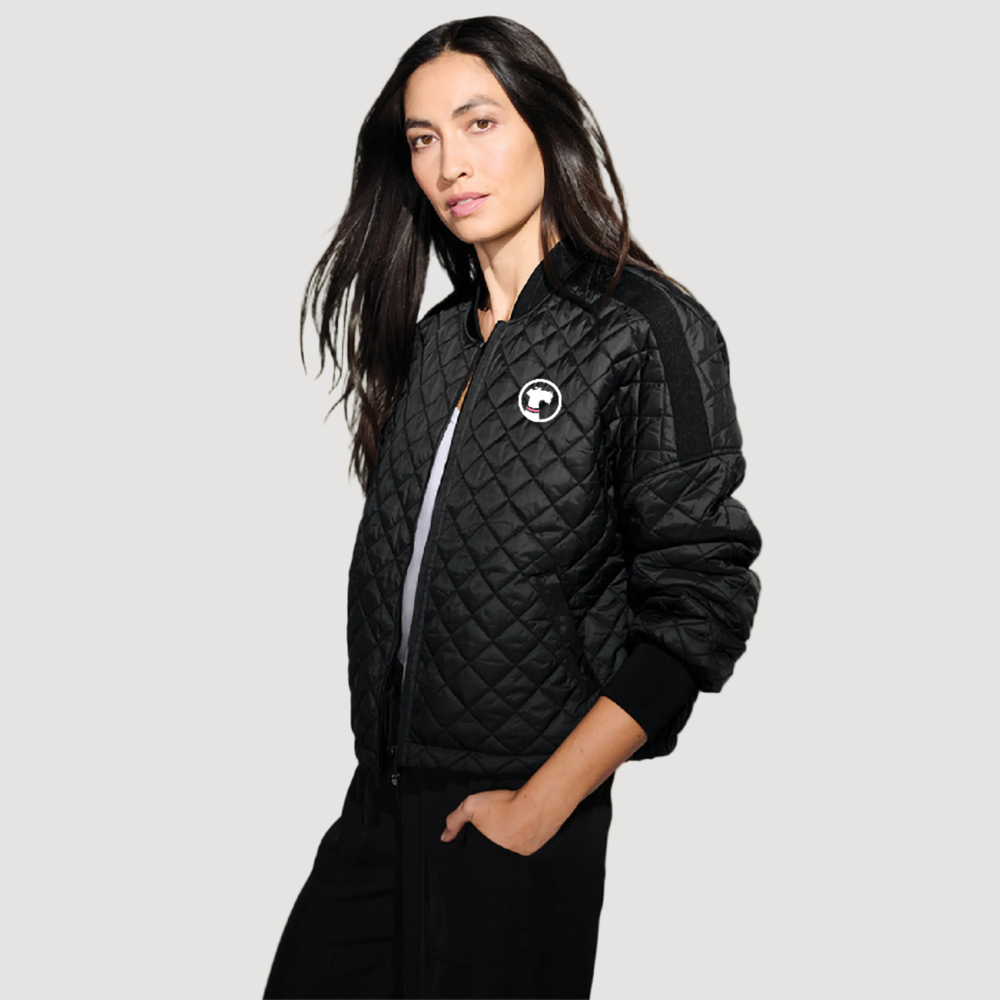 Woman wearing a black quilted jacket with a logo on a white background